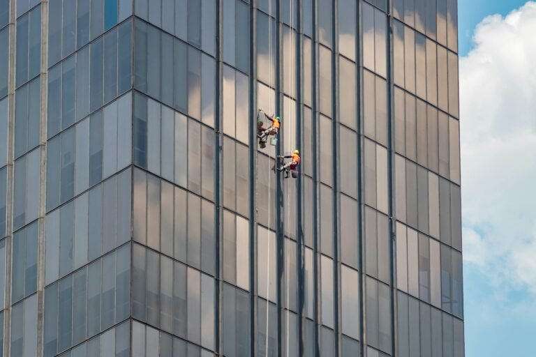 Two window cleaners working on a modern office building in Ciudad de México.