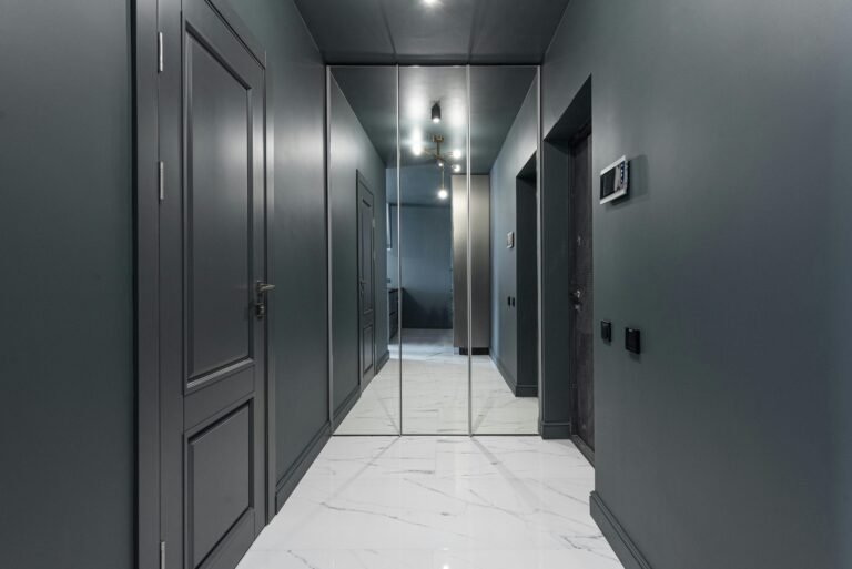 Sleek and contemporary hallway interior with mirror doors and marble flooring.